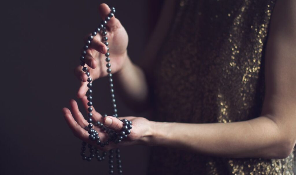 Femme tenant un collier de perles noires, style moderne et élégant