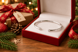 Silver open bangle with small diamonds in a red jewelry box on a Christmas table setting.